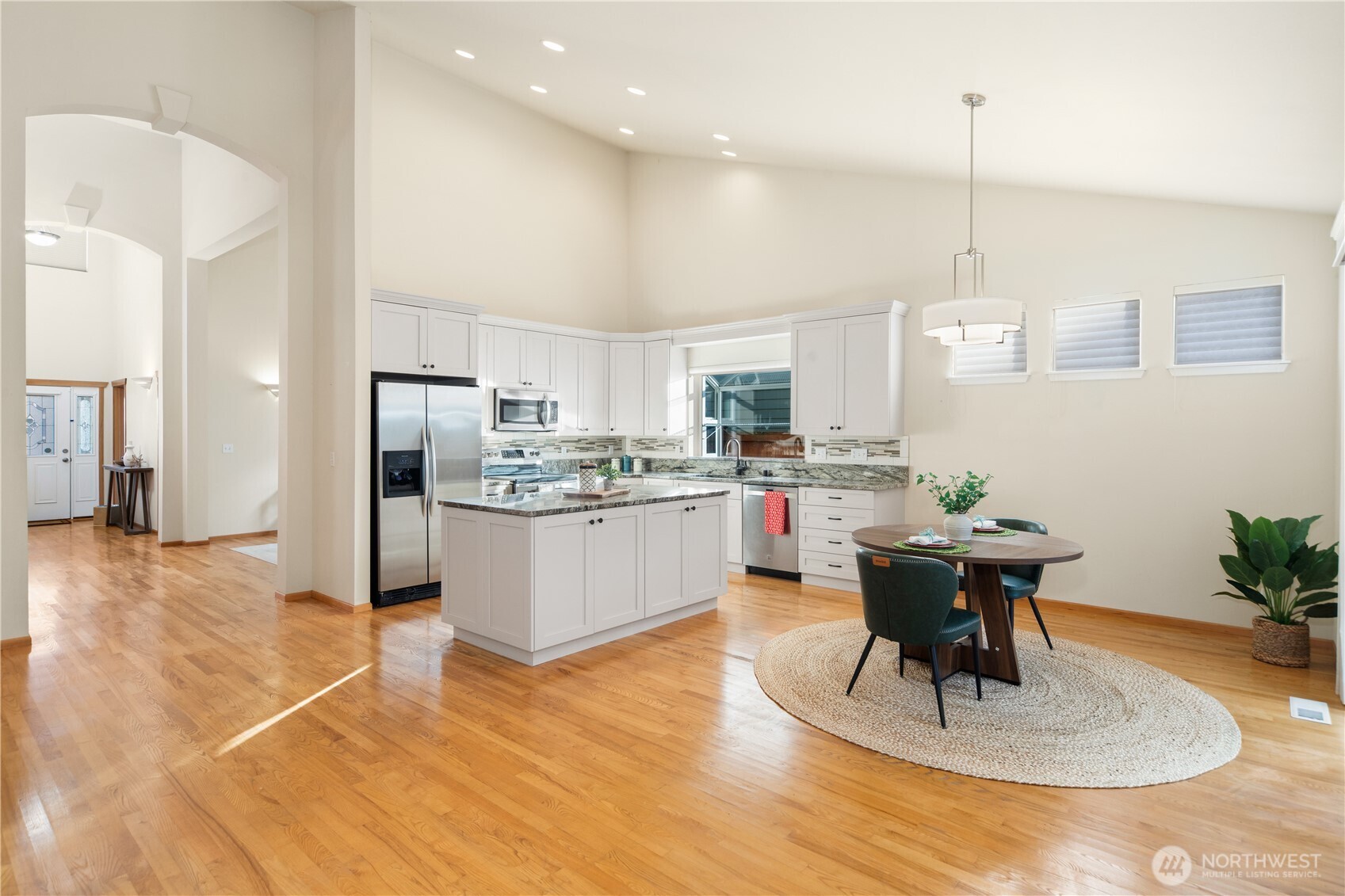 18130 Sunrise Ridge Avenue Northeast Poulsbo, WA 98370 - Photo 10 of 30 a kitchen with stainless steel appliances kitchen island granite countertop a stove a refrigerator a sink a dining table and chairs with wooden floor
