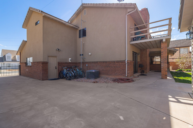 892 Cambridge Drive St. George, UT 84770 - Photo 62 of 65 Spacious concrete driveway with brick accents, featuring an upper-level balcony with wood railing and a covered patio area below