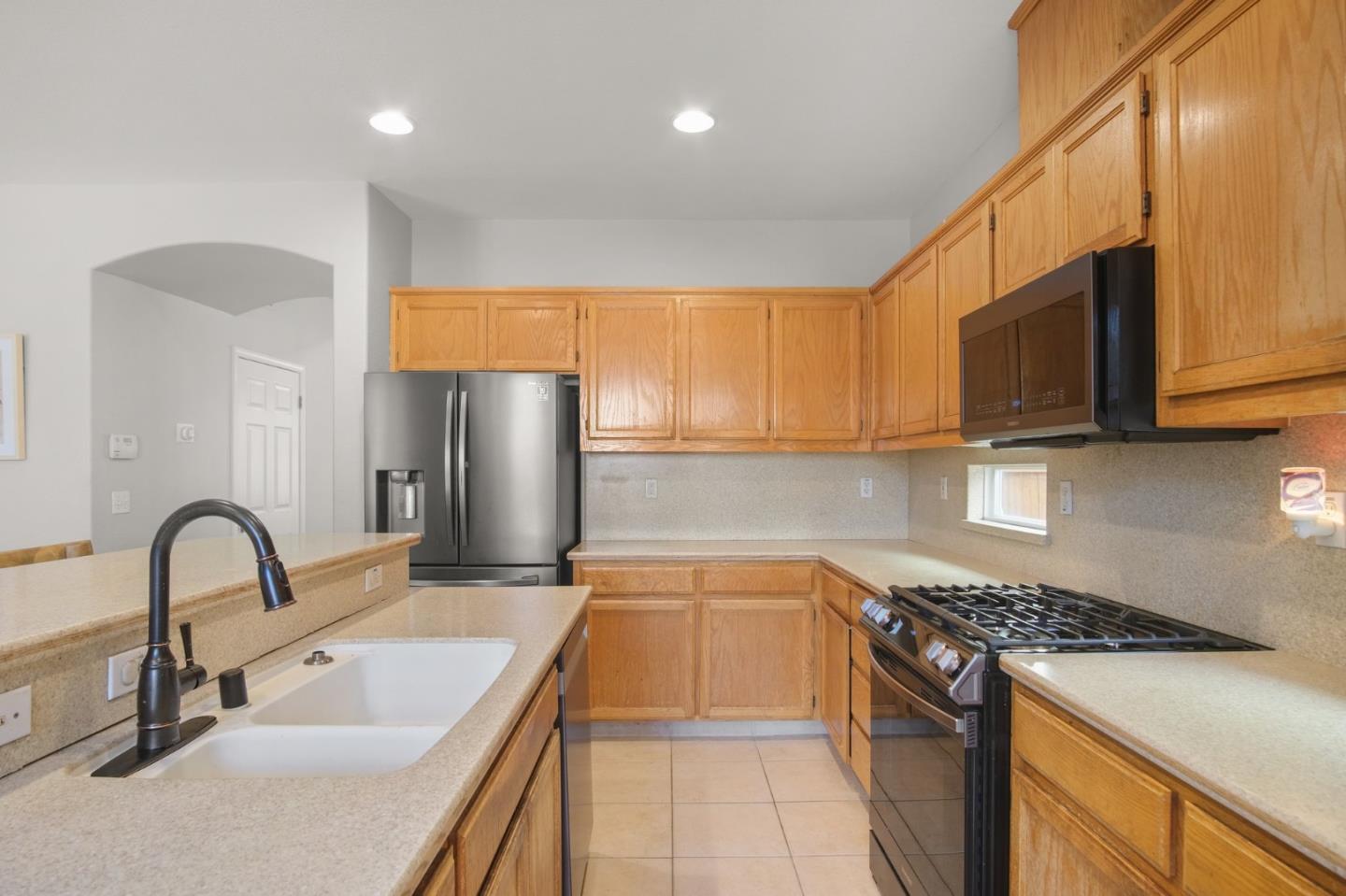 3021 Simms Lane Tracy, CA 95377 - Photo 21 of 33 a kitchen with stainless steel appliances granite countertop a sink a stove and a refrigerator with wooden cabinets