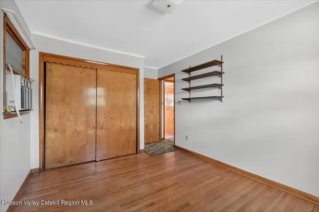 an empty room with wooden floor closet and windows
