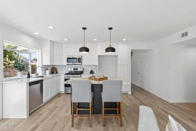 a living room with furniture white walls and kitchen view