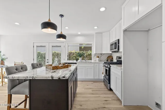 a view of a kitchen with kitchen island granite countertop wooden floor stainless steel appliances and dining table