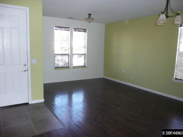 490 Dartmoor Court Reno, NV 89521 - Photo 3 of 8 an empty room with wooden floor cabinet and windows