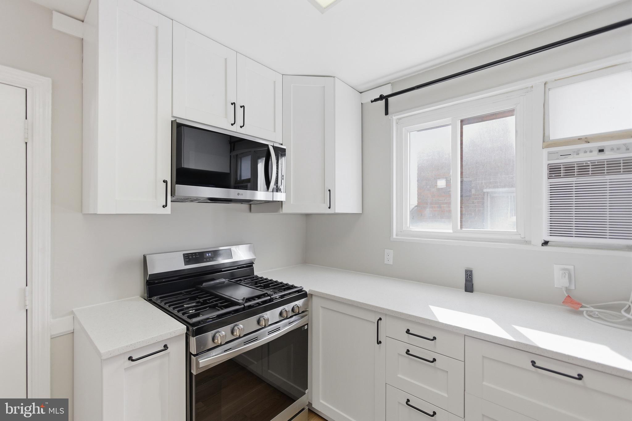 7519 8th Street Northwest Washington, DC 20012 - Photo 4 of 19 a kitchen with stainless steel appliances white cabinets and a stove top oven