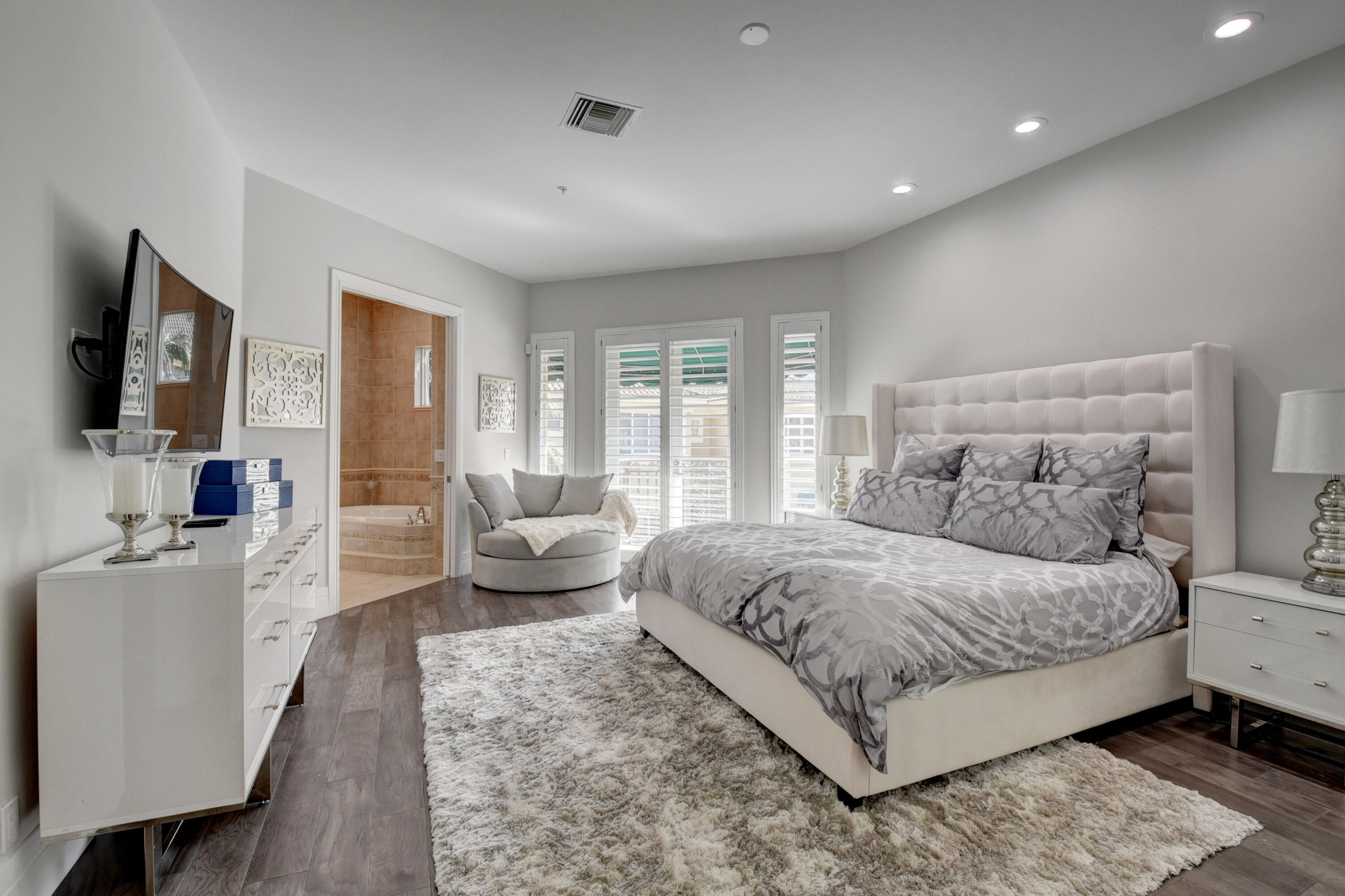 921 Osceola Drive, Unit 4 Boca Raton, FL 33432 - Photo 31 of 46 a bedroom with a large bed couch and a flat tv screen