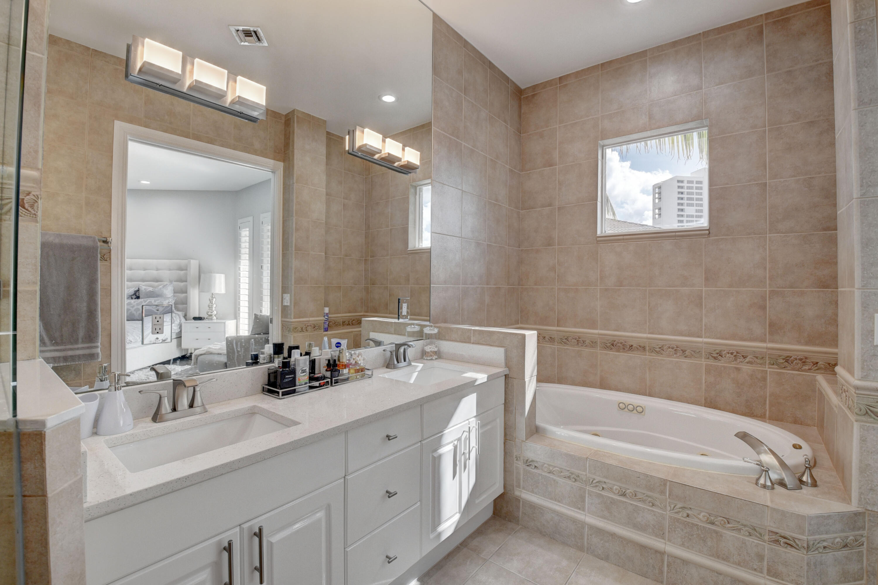 921 Osceola Drive, Unit 4 Boca Raton, FL 33432 - Photo 34 of 46 a bathroom with a bathtub a double vanity sink and a mirror