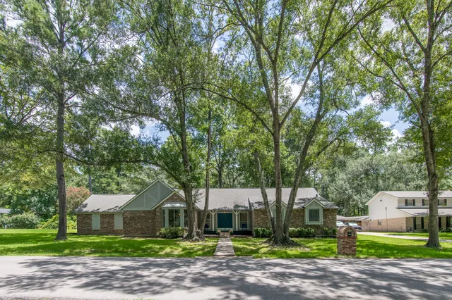 a front view of a house with a garden and trees