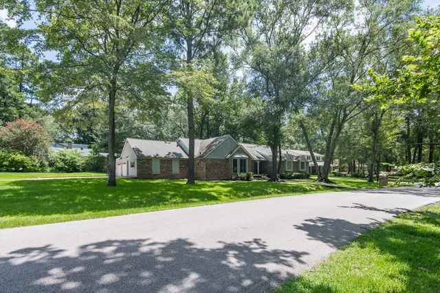 a view of a house with a yard and large trees