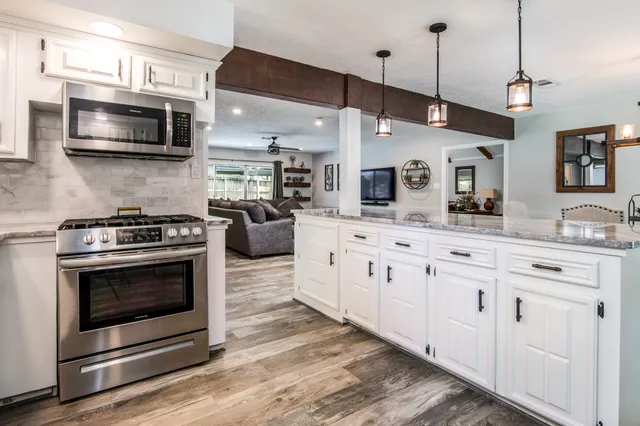 a kitchen with stainless steel appliances granite countertop a stove a microwave and wooden floors