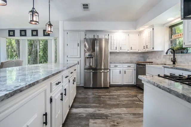 a kitchen with granite countertop a sink stainless steel appliances and window