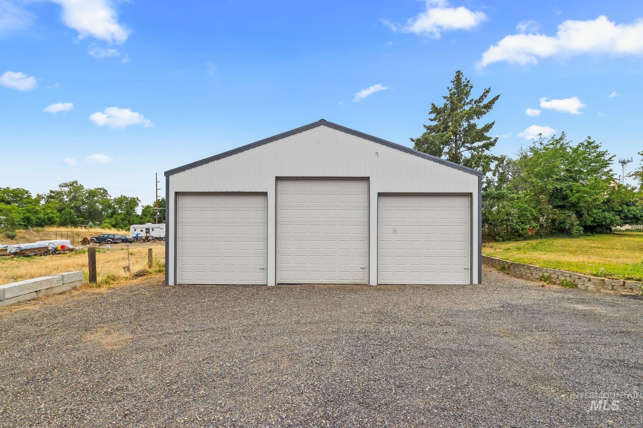 2255 Appleside Boulevard Clarkston, WA 99403 - Photo 35 of 41 Detached metal building featuring three overhead garage doors, a sloped roofline, and gravel driveway