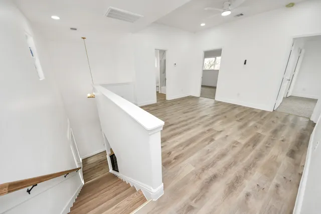 an empty room with windows and ceiling fan