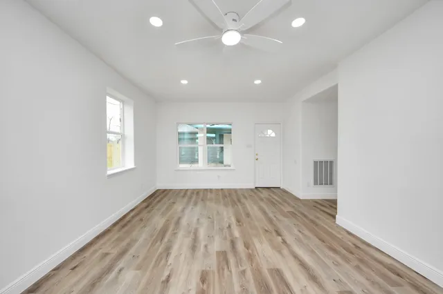 an empty room with wooden floor and windows
