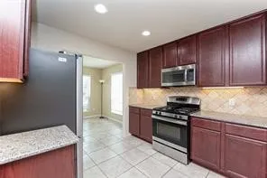 a kitchen with granite countertop wooden cabinets and stainless steel appliances
