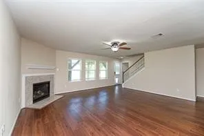 an empty room with wooden floor fireplace and windows