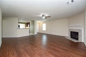 an empty room with wooden floor fireplace and windows