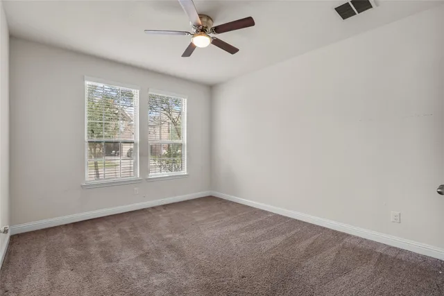 an empty room with a ceiling fan and window