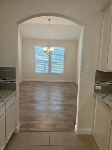 a view of an empty room with wooden floor fireplace and a window