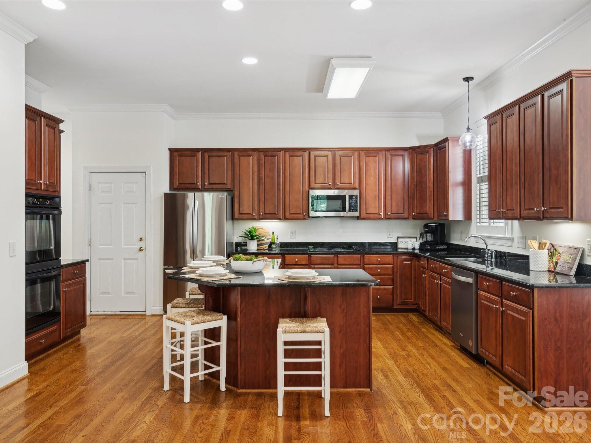927 Derick's Crossing Fort Mill, SC 29708 - Photo 21 of 48 a kitchen with stainless steel appliances granite countertop wooden cabinets a stove a sink a refrigerator and island with wooden floor
