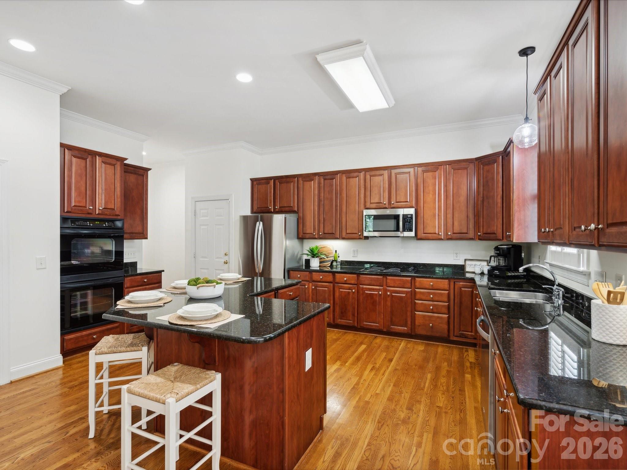 927 Derick's Crossing Fort Mill, SC 29708 - Photo 22 of 48 a kitchen with stainless steel appliances granite countertop a stove top oven a sink dishwasher a dining table and chairs with wooden floor