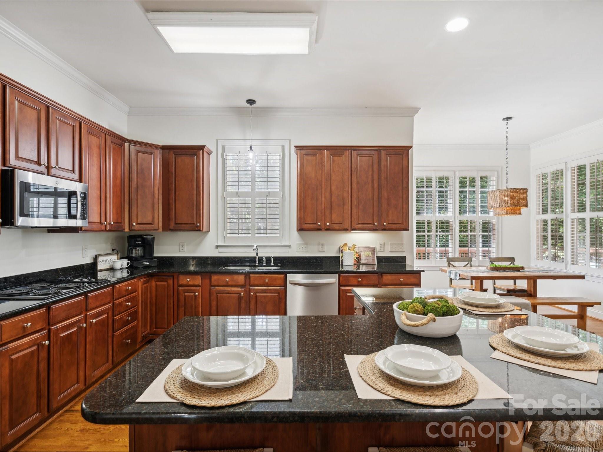 927 Derick's Crossing Fort Mill, SC 29708 - Photo 23 of 48 a kitchen with a sink a stove a kitchen island and couches wooden cabinets with granite countertops
