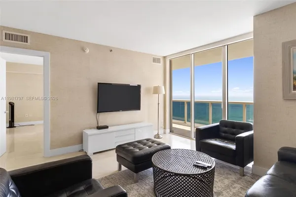 a living room with furniture a flat screen tv and a large window