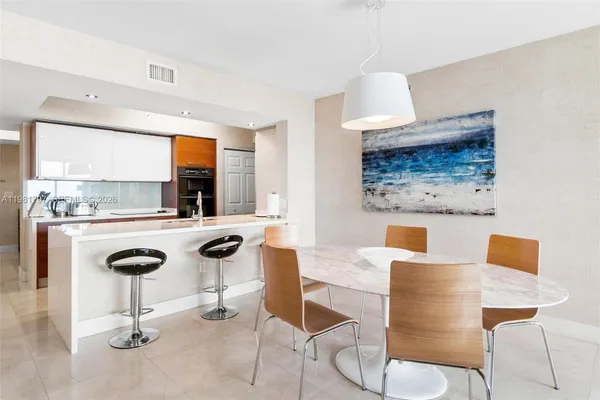 a kitchen with stainless steel appliances kitchen island granite countertop a table and chairs in it