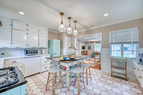 a kitchen with stainless steel appliances kitchen island granite countertop a sink a stove a dining table and chairs