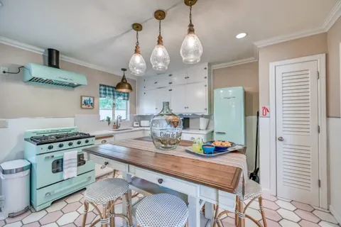 a kitchen with stainless steel appliances granite countertop a stove a refrigerator a kitchen island a dining table and chairs with wooden floor