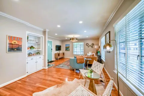 a living room with furniture a wooden floor and next to a window