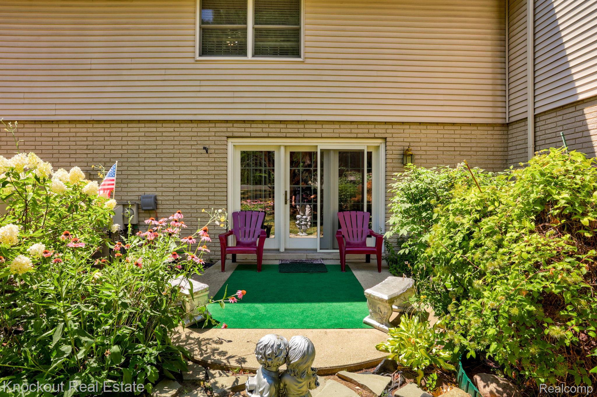249 Churchgrove Road Frankenmuth, MI 48734 - Photo 36 of 44 Ground-level patio area featuring a sliding glass door, a brick exterior, and surrounding garden beds with established plantings