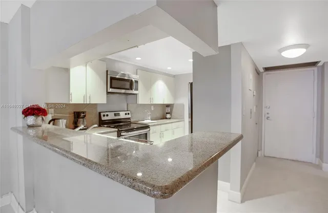 a kitchen with stainless steel appliances granite countertop a sink a stove and a refrigerator