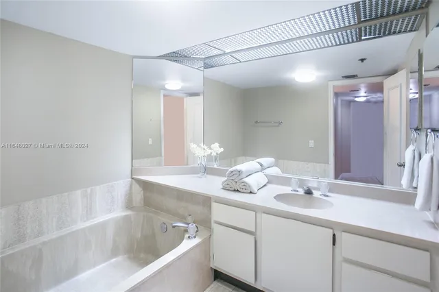 a bathroom with a bathtub sink vanity and mirror