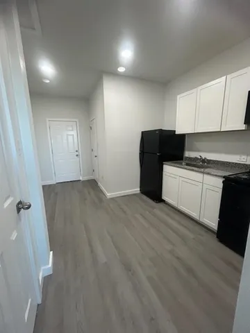 a view of a kitchen with a sink and dishwasher a refrigerator with wooden floor