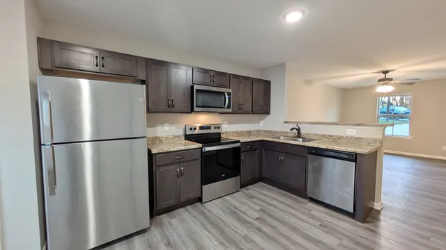 a kitchen with granite countertop a refrigerator stove top oven and sink