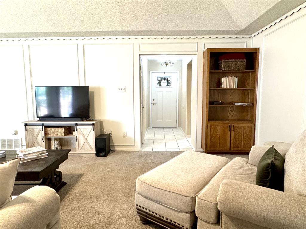 113 Northeast Timber Ridge Drive Burleson, TX 76028 - Photo 4 of 36 Entry OPENS to Living Room featuring light-toned carpet, white paneled walls, and a recessed entryway with tile flooring