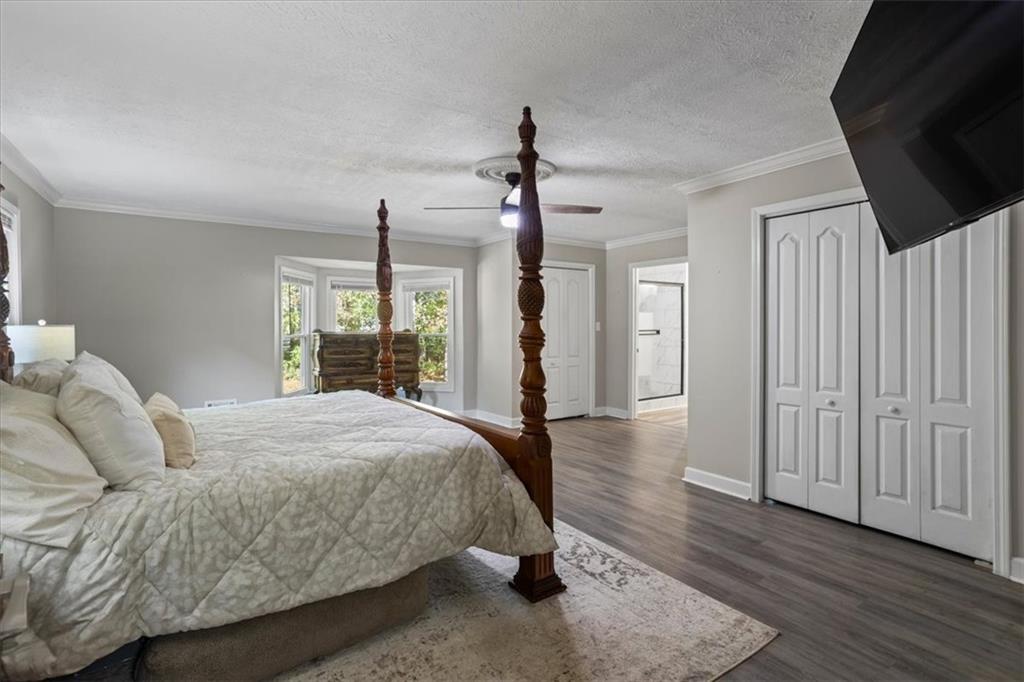 564 Eskew Road McDonough, GA 30252 - Photo 17 of 54 a spacious bedroom with a bed a flat screen tv and a chandelier