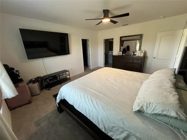 a spacious bedroom with a bed and a flat screen tv