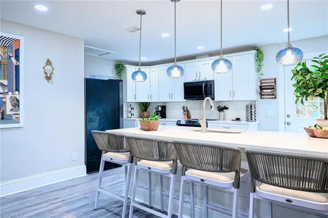 a kitchen with kitchen island stainless steel appliances a table chairs sink and wooden floor
