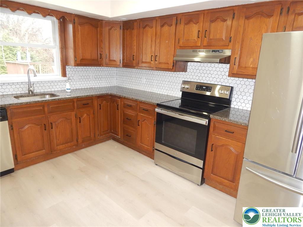 4117 Grape Street Coplay, PA 18037 - Photo 6 of 41 a kitchen with stainless steel appliances granite countertop wooden cabinets a stove a sink and a window