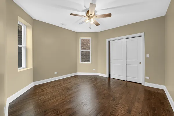 a view of an empty room with window and wooden floor