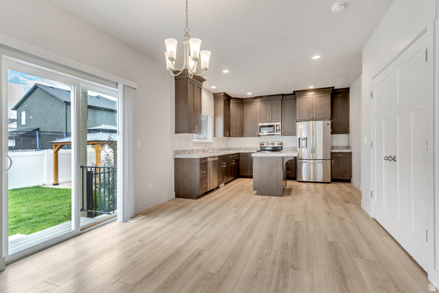 4572 Flower Point Eagle Mountain, UT 84005 - Photo 15 of 62 Open-concept kitchen and dining area featuring light wood-finish flooring, a kitchen island, stainless steel appliances, and dark wood cabinetry