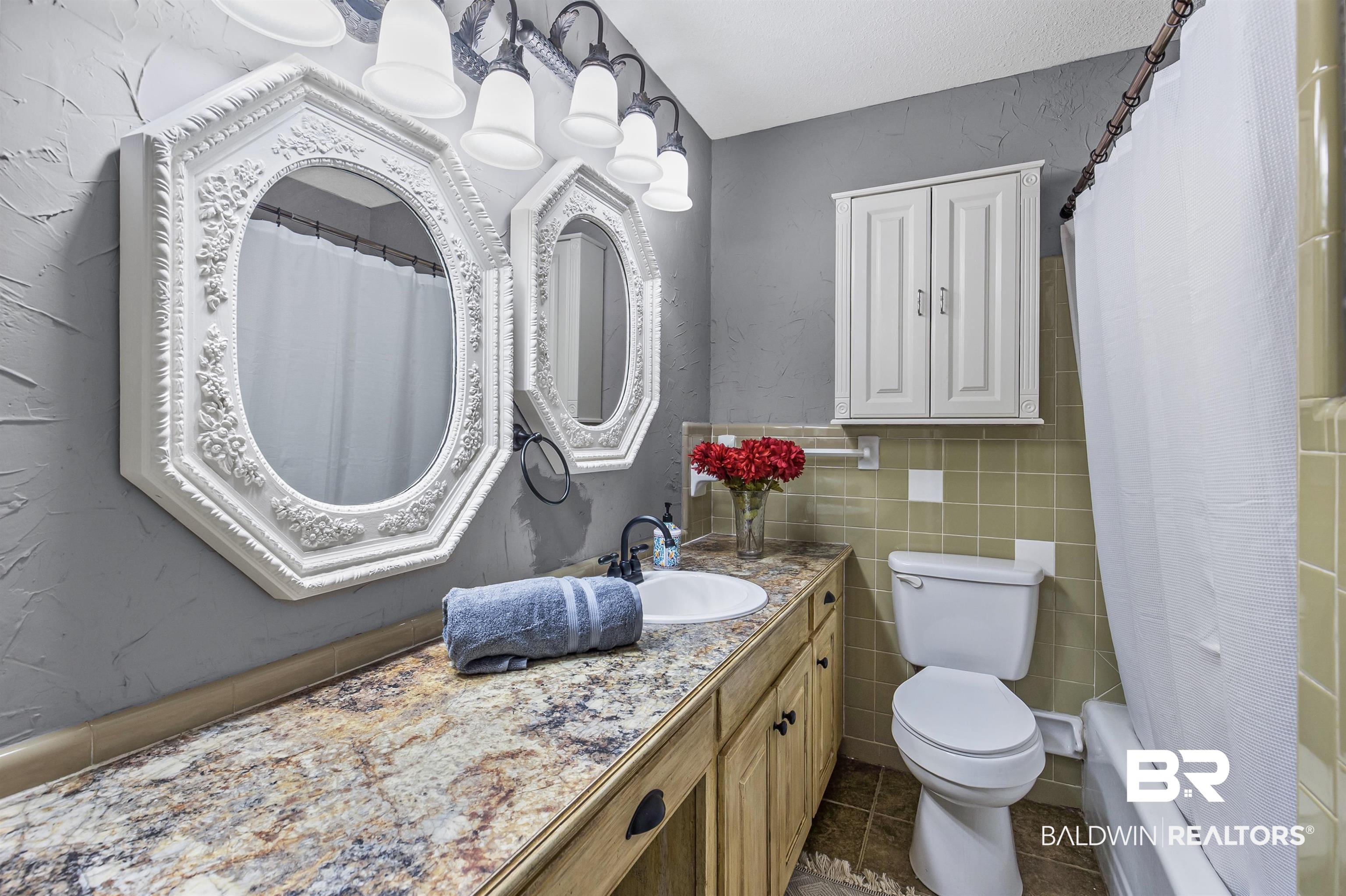 36 Ridgeview Drive Mobile, AL 36611 - Photo 12 of 20 Full bathroom in hallway featuring vanity, shower / bath combo with shower curtain, tile walls, dark tile patterned flooring, and a textured wall