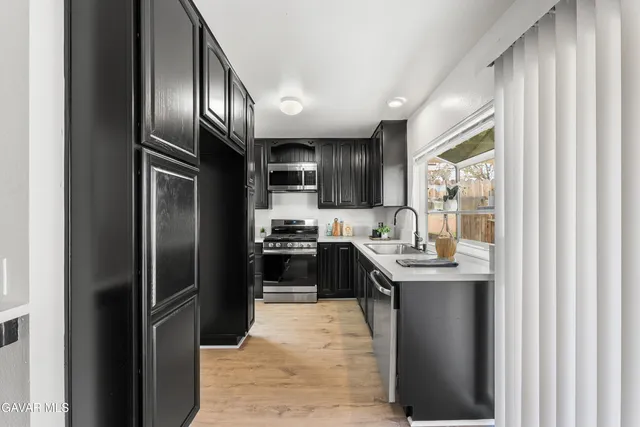 a kitchen with stainless steel appliances granite countertop a refrigerator a sink a stove and oven