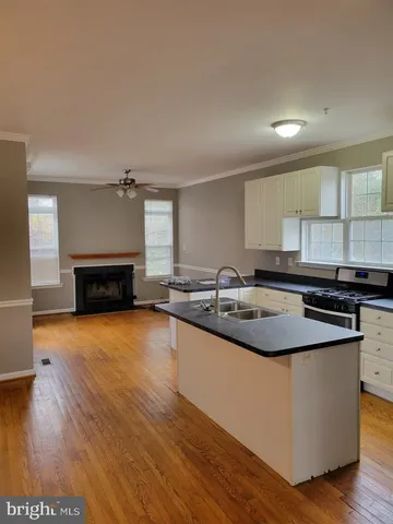 a kitchen with stainless steel appliances granite countertop a sink a stove and a wooden floors