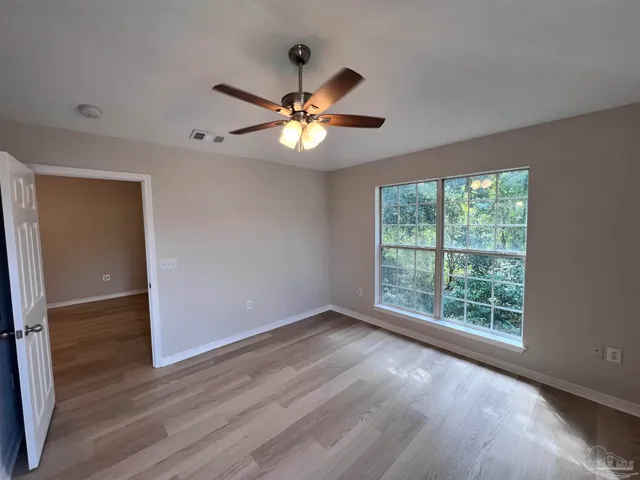 a view of an empty room with a window and wooden floor