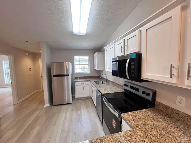 a kitchen with stainless steel appliances granite countertop a stove a refrigerator and a microwave