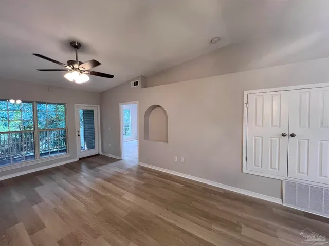 a view of an empty room with wooden floor and a window