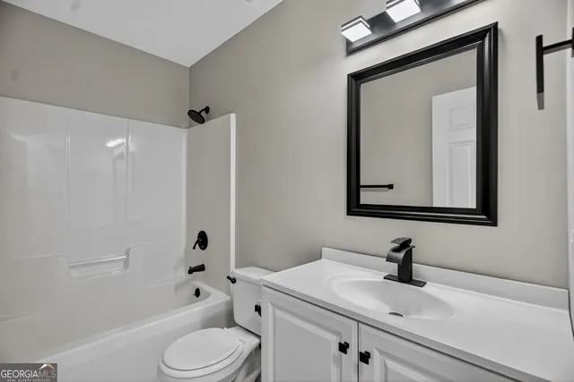 a bathroom with a toilet sink vanity tub and mirror