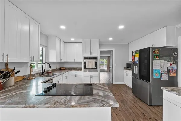 a large kitchen with granite countertop a large counter top stainless steel appliances and cabinets